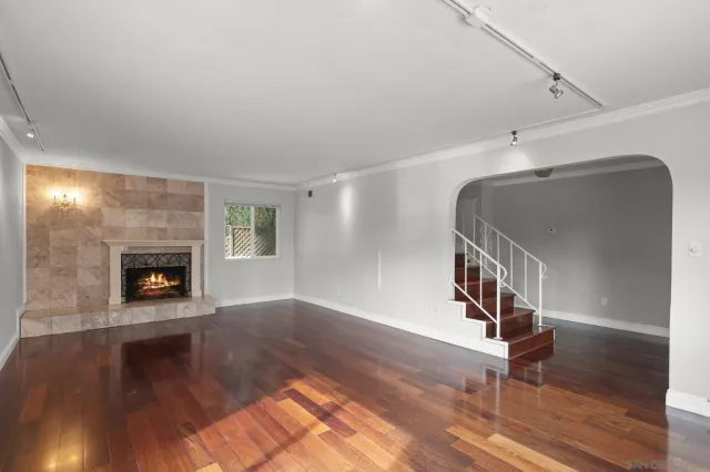 a view of an empty room with window and wooden floor