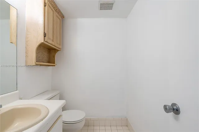 a white toilet sitting next to a white sink and vanity