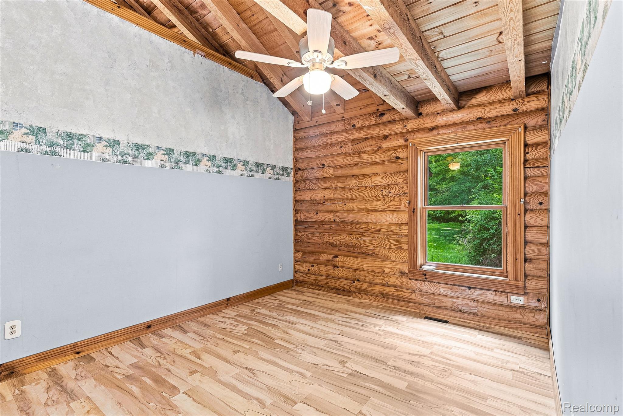 8340 North Nichols Road Flushing, MI 48433 - Photo 24 of 62 Exposed wood beam ceiling with a ceiling fan, log wall paneling, wood-finish flooring, and a window with wood trim