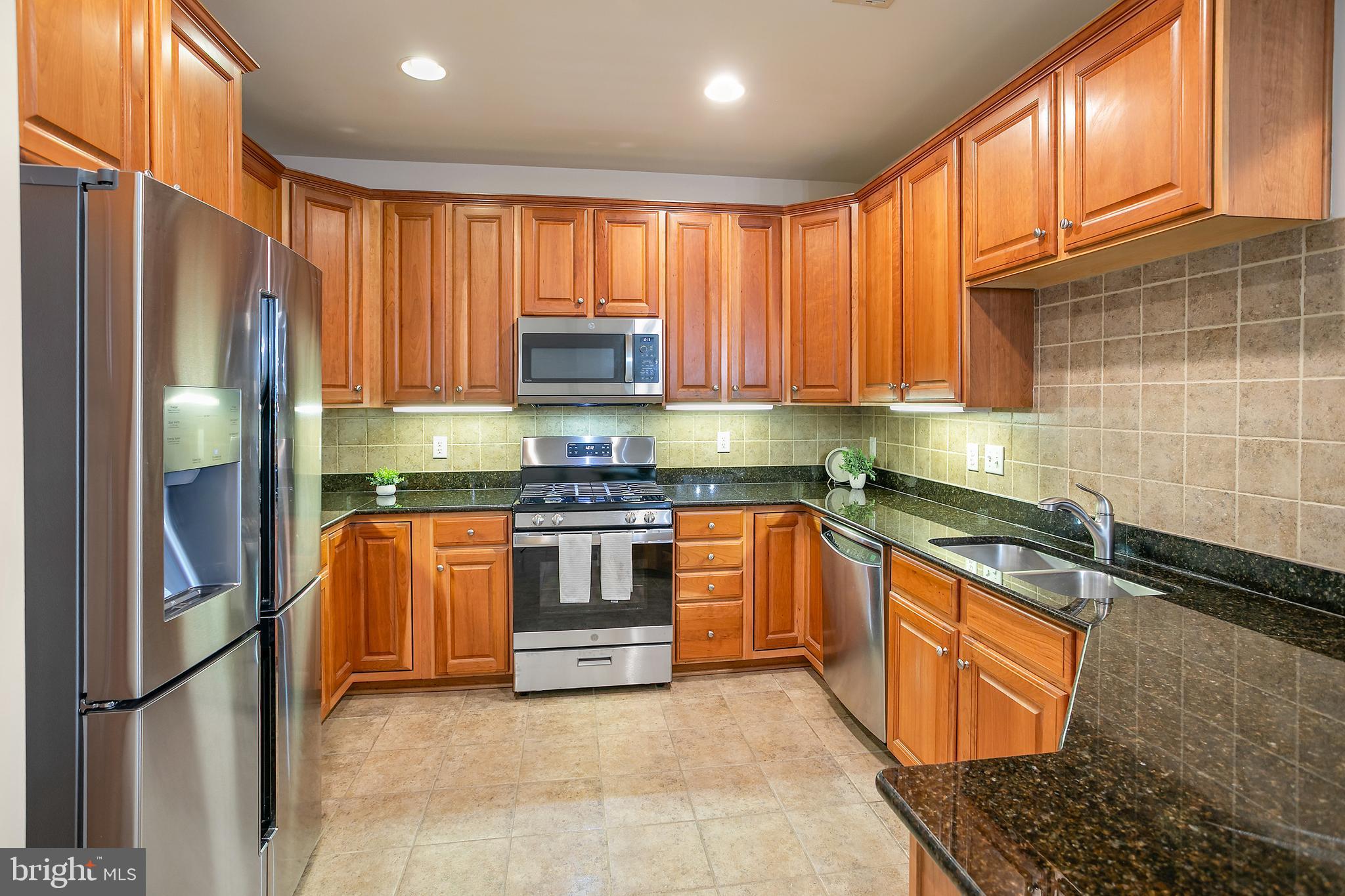 400 Cameron Station Boulevard, Unit 308 Alexandria, VA 22304 - Photo 2 of 46 a kitchen with stainless steel appliances granite countertop a refrigerator a stove and a sink with wooden cabinets