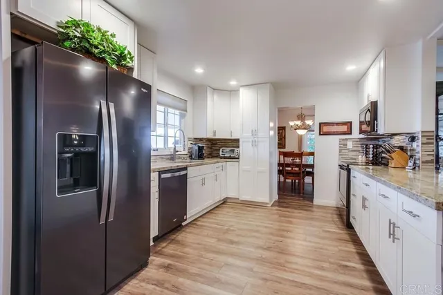 a kitchen with stainless steel appliances granite countertop a refrigerator a stove and a sink