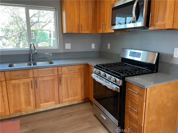 a kitchen with granite countertop white cabinets stainless steel appliances and a window