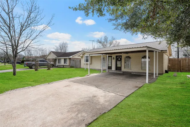 a view of house with a big yard and large trees
