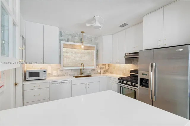 a kitchen with white cabinets appliances and sink