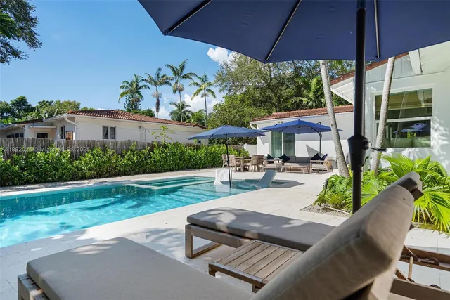 a view of a patio with couches table and chairs under an umbrella