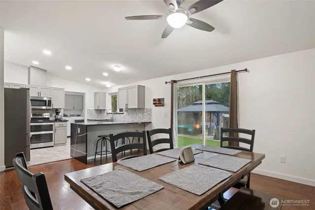 a living room with stainless steel appliances furniture a rug and a window