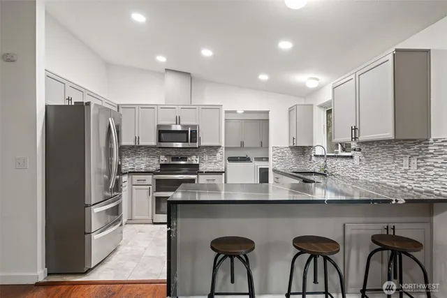 a kitchen with stainless steel appliances granite countertop a table chairs sink refrigerator and microwave