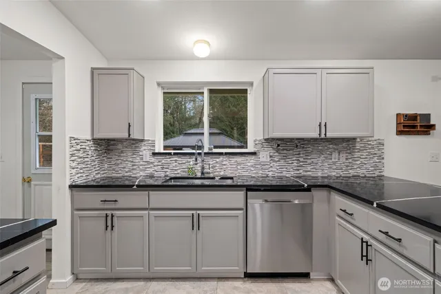 a kitchen with granite countertop a sink and a white wooden cabinets