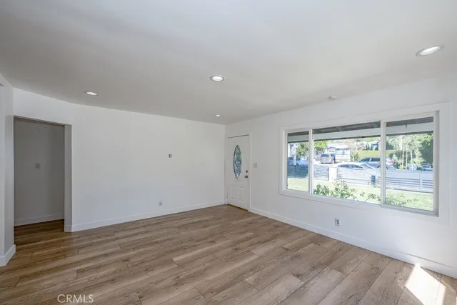 a view of an empty room with wooden floor and a window