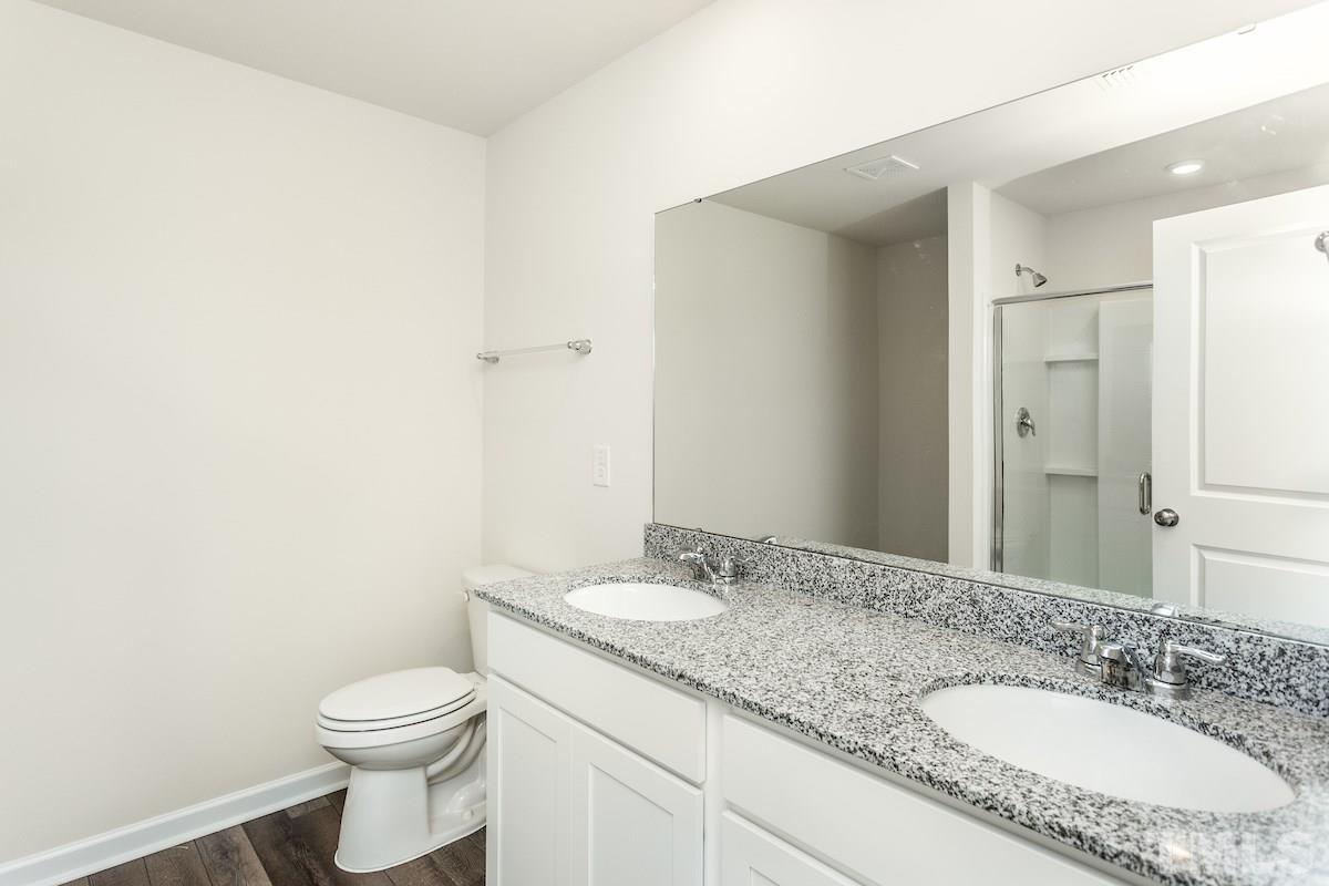 3517 Strawberry Patch Row Raleigh, NC 27604 - Photo 5 of 11 a bathroom with a granite countertop sink a toilet and a mirror