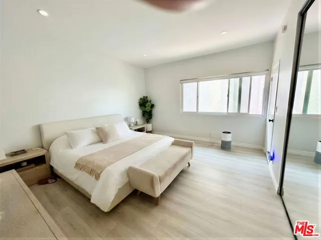 a spacious bedroom with a bed and a potted plant on dresser
