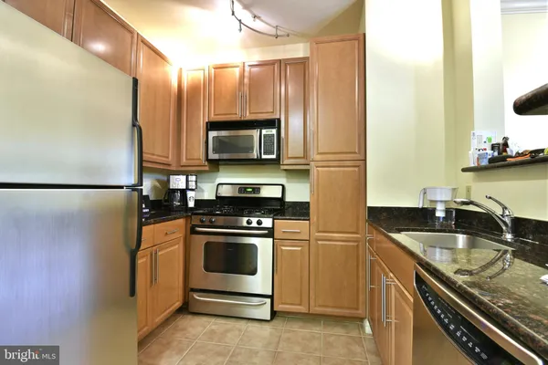 a kitchen with granite countertop a sink stove and refrigerator