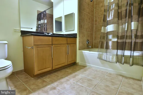 a bathroom with a granite countertop sink a toilet and bathtub
