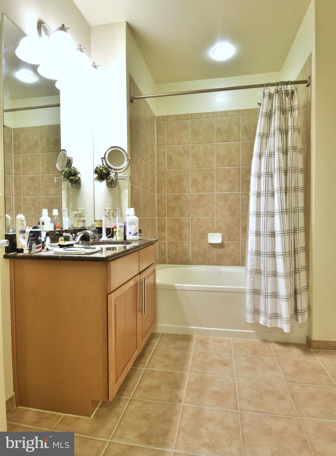 11770 Sunrise Valley Drive, Unit 120 Reston, VA 20191 - Photo 27 of 41 a bathroom with a granite countertop sink a mirror and a bathtub