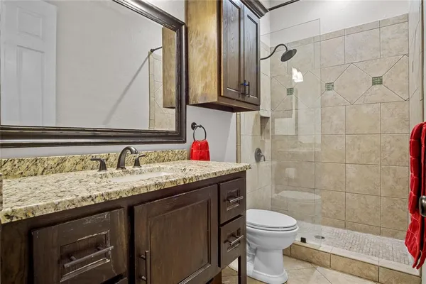 a bathroom with a granite countertop toilet sink and mirror