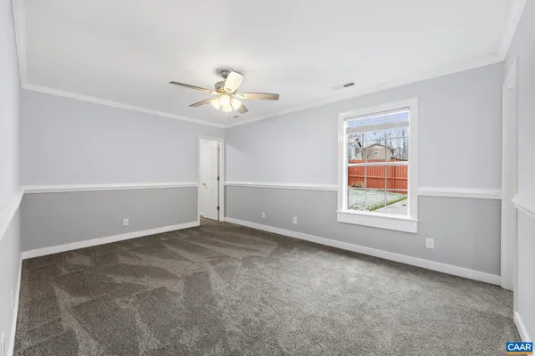 an empty room with windows and chandelier fan