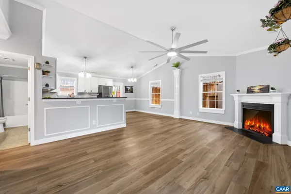 a view of an empty room with kitchen and fireplace