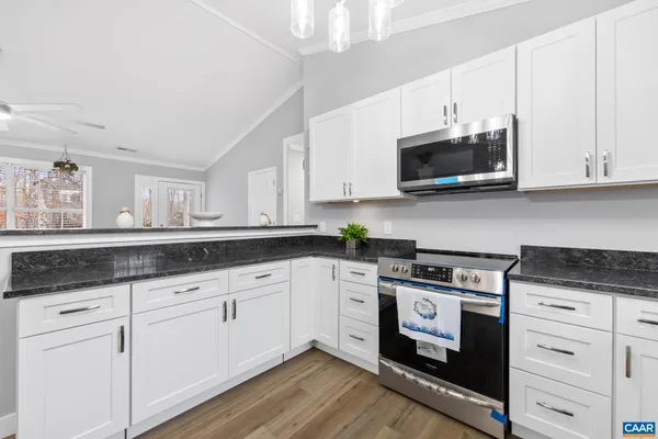 a kitchen with granite countertop white cabinets white stainless steel appliances and a sink