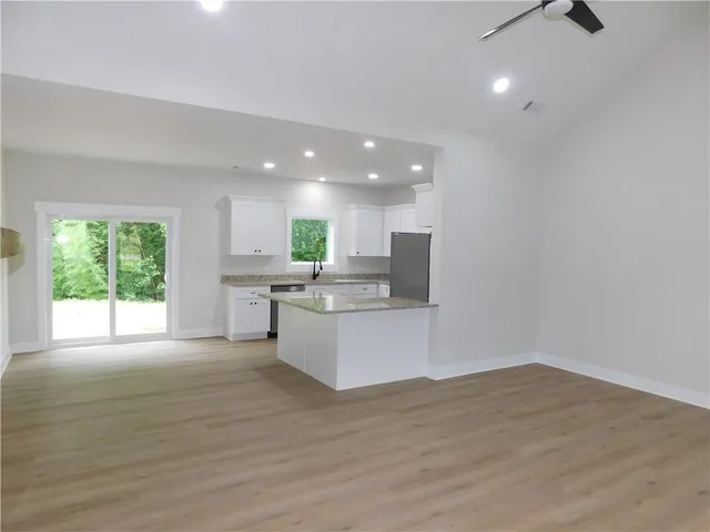 a large white kitchen with kitchen island granite countertop a large counter top and stainless steel appliances