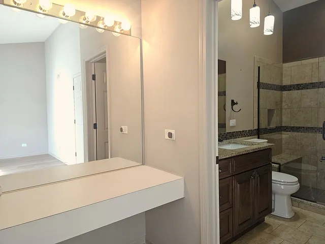 a bathroom with a granite countertop sink a toilet a mirror and vanity