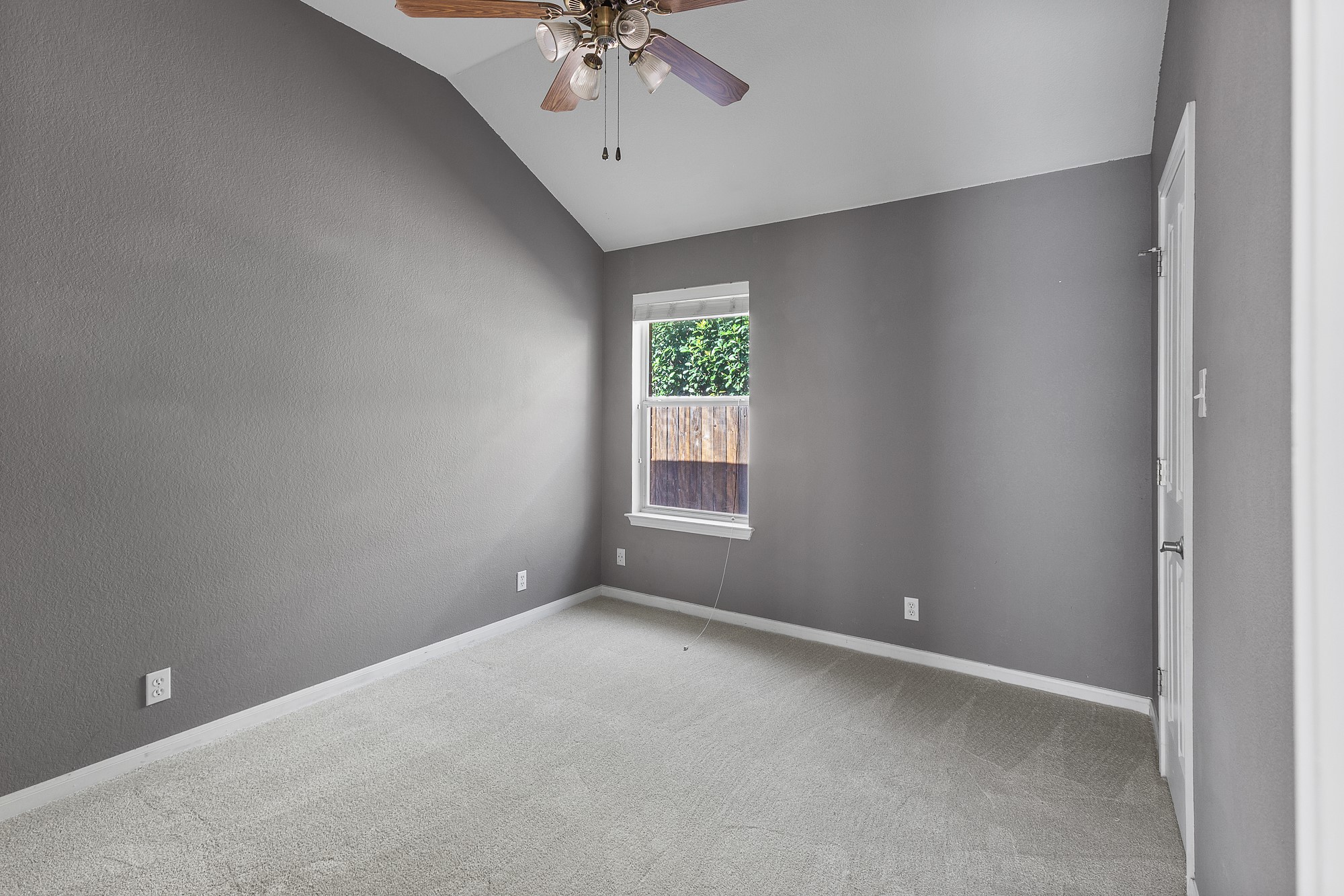 1201 Springbrook Road Pflugerville, TX 78660 - Photo 18 of 33 A well-lit bedroom with vaulted ceilings and a ceiling fan, offering a comfortable personal retreat.