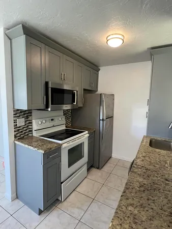 a kitchen with stainless steel appliances granite countertop a stove a refrigerator and a sink with wooden floor