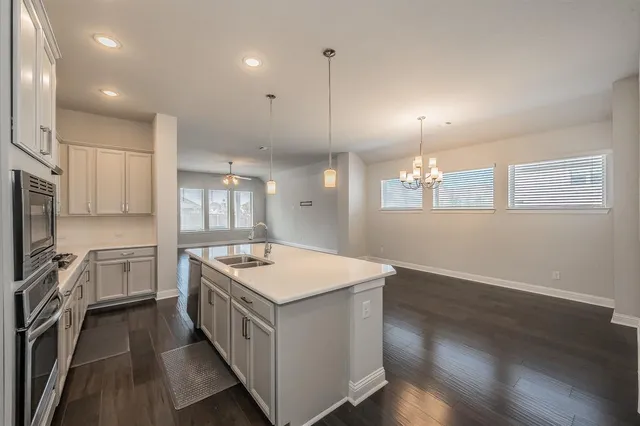 a view of a kitchen with stainless steel appliances granite countertop a refrigerator a sink dishwasher a oven and a dining table with wooden floor