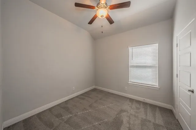 an empty room with chandelier fan and windows