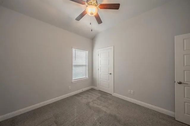 an empty room with a chandelier fan and closet