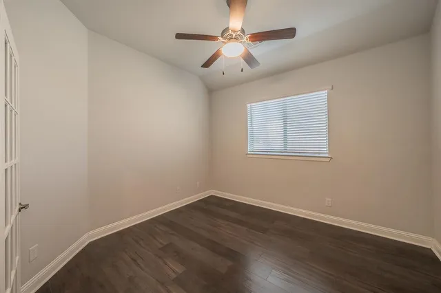 an empty room with wooden floor and ceiling fan
