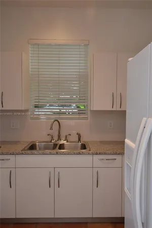 a kitchen with granite countertop white cabinets and a sink