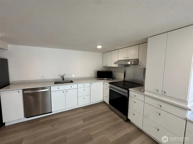 a kitchen with granite countertop white cabinets and stainless steel appliances