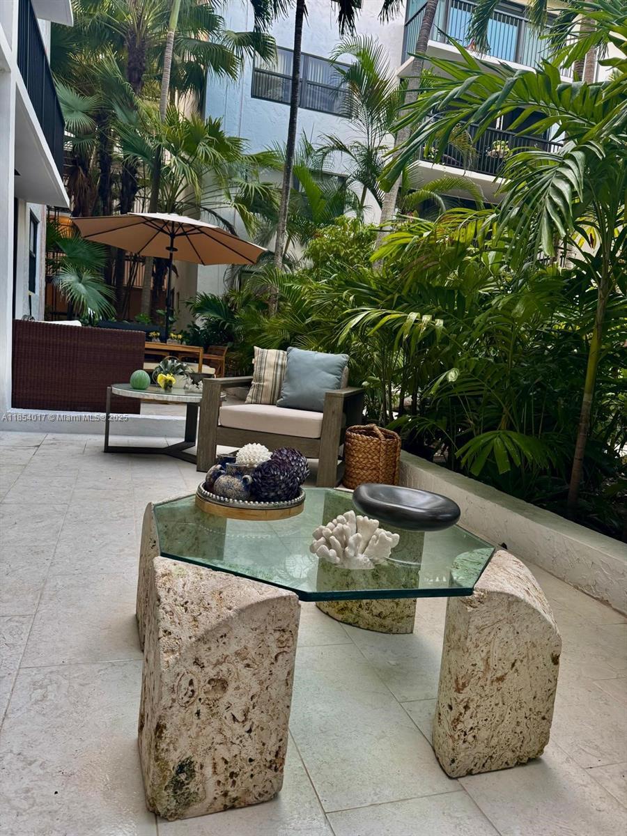 55 Ocean Ln Drive, Unit 1018 Key Biscayne, FL 33149 - Photo 34 of 36 a view of a patio with couches table and chairs under an umbrella with a fire pit