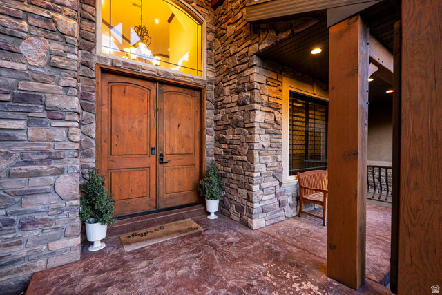 687 South 2080th Street East Springville, UT 84663 - Photo 130 of 149 Grand entryway featuring natural stone veneer, double wood-paneled doors, an arched transom window, a stained concrete porch, and substantial wood support beams
