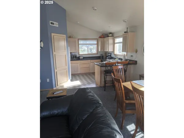 a living room with stainless steel appliances kitchen island granite countertop furniture and a refrigerator