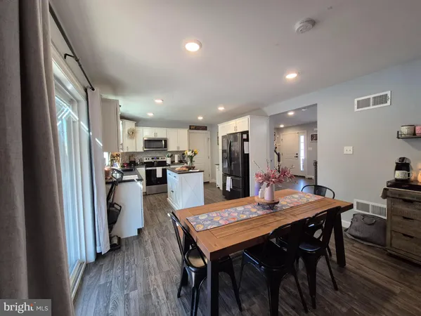 a kitchen with a refrigerator a dining table and chairs