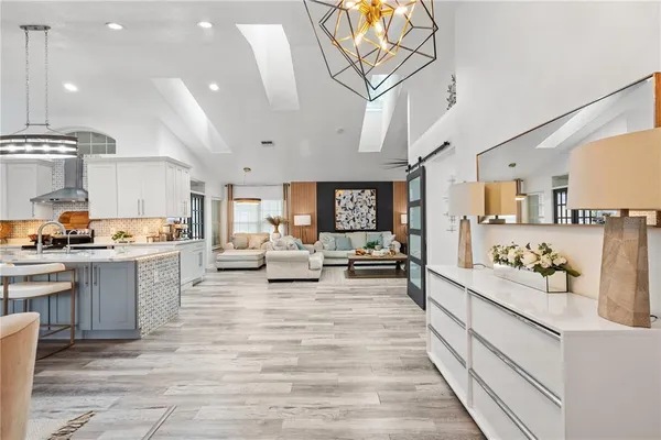a large white kitchen with lots of counter space and chandelier