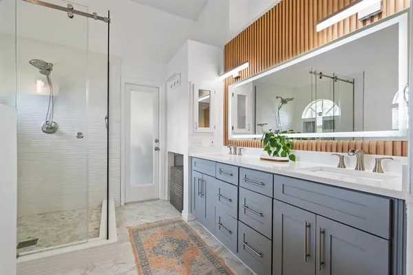 a spacious bathroom with a double vanity sink mirror and shower