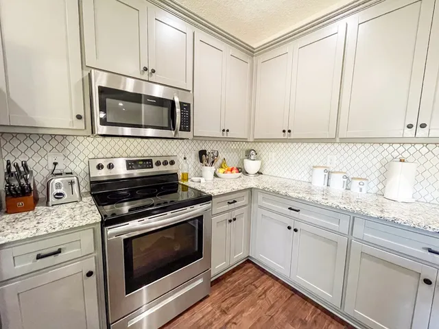 a kitchen with granite countertop white cabinets stainless steel appliances and a sink