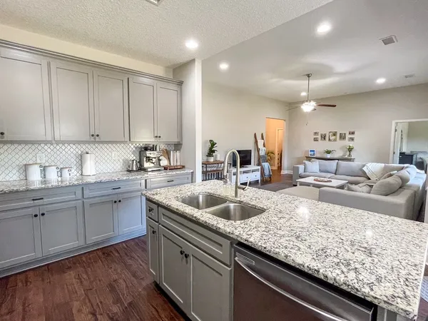 a kitchen with granite countertop a sink a counter space appliances and cabinets