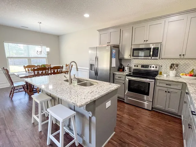 a kitchen with stainless steel appliances granite countertop a kitchen island hardwood floor sink stove dining table and chairs