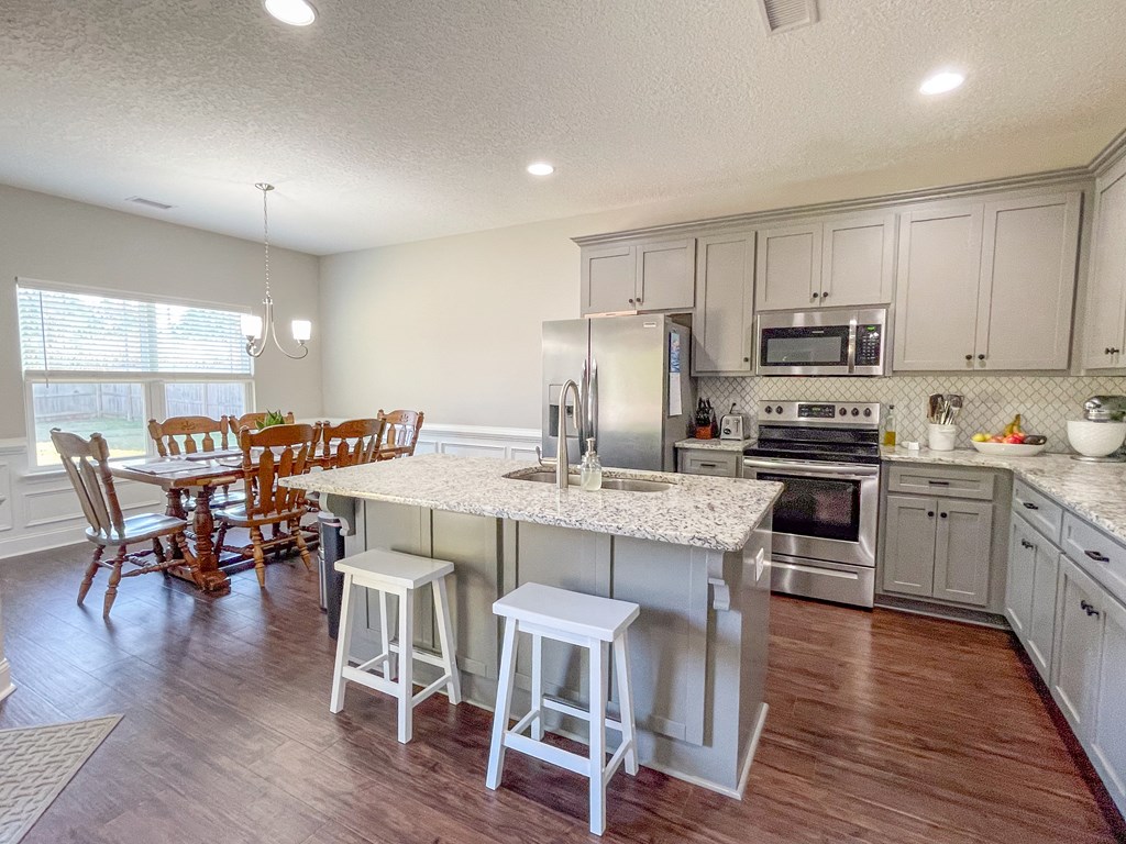 6 Cheyenne Trail Fort Mitchell, AL 36856 - Photo 8 of 33 a kitchen with stainless steel appliances granite countertop a stove top oven a refrigerator a dining table and chairs with wooden floor