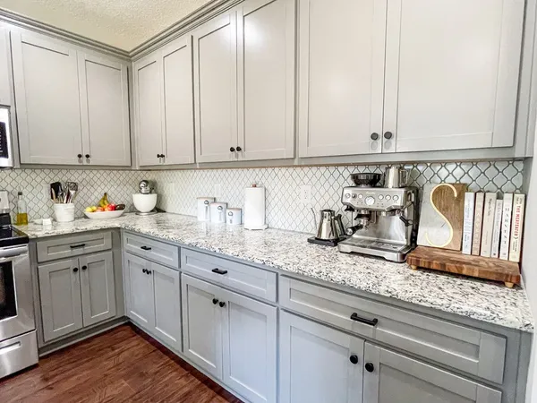 a kitchen with granite countertop white cabinets and white appliances