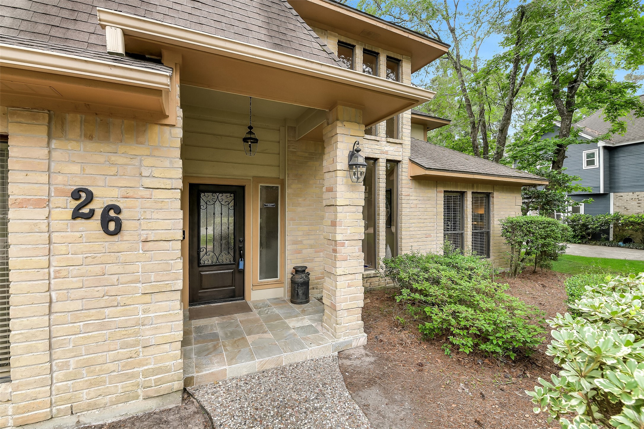 26 Split Rock Road Spring, TX 77381 - Photo 3 of 40 Charming brick home with a welcoming front entryway, featuring a stylish door and elegant lantern. Surrounded by lush greenery, it offers a cozy, inviting atmosphere.
