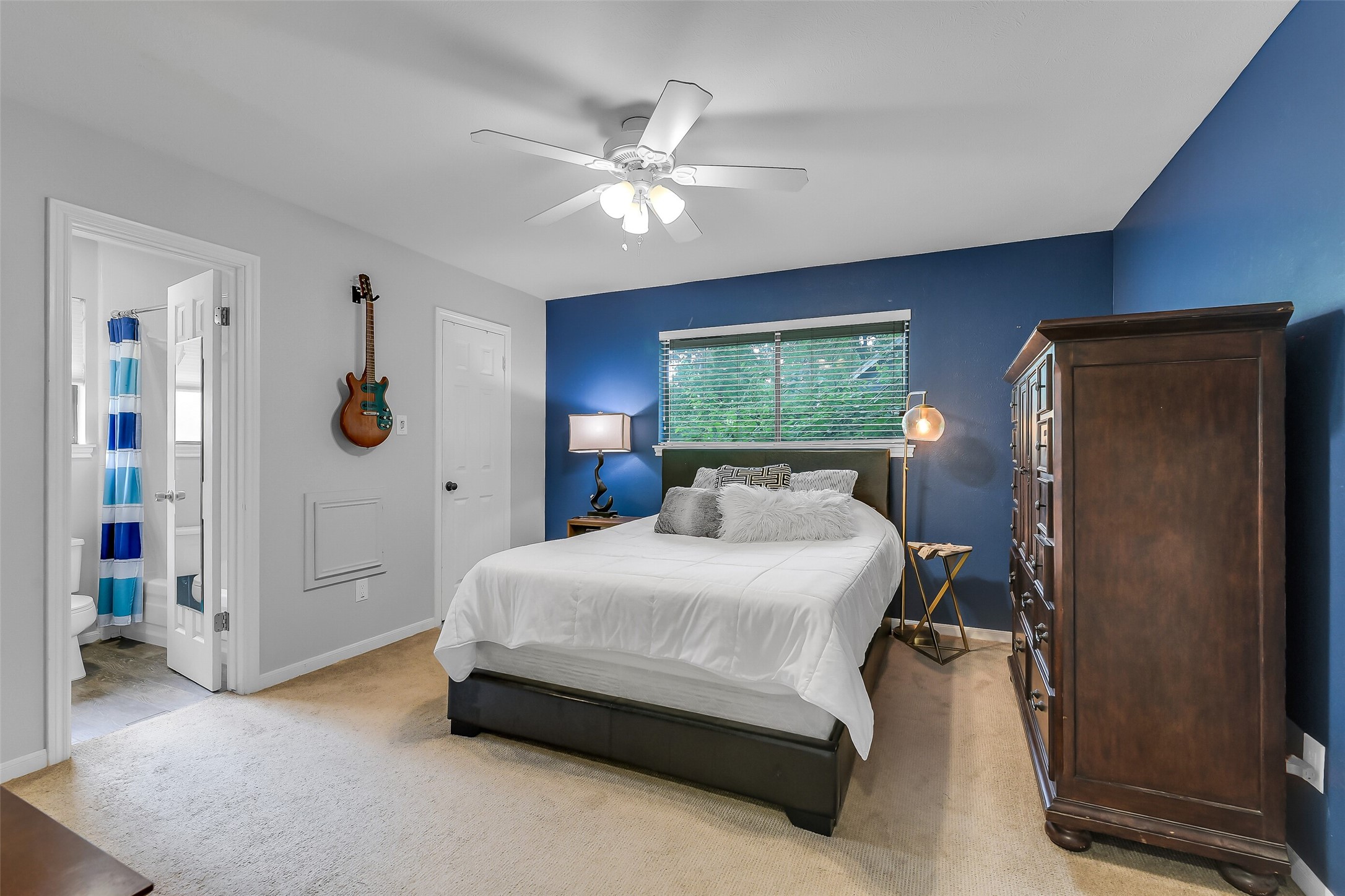 26 Split Rock Road Spring, TX 77381 - Photo 31 of 40 This cozy second bedroom features a plush carpet and a striking blue accent wall. It offers ample natural light through a large window, and includes a ceiling fan for comfort.