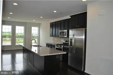 a kitchen with stainless steel appliances granite countertop a refrigerator a sink a stove a counter space and cabinets