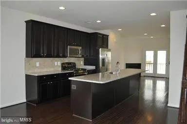 a kitchen with stainless steel appliances granite countertop a sink a stove a refrigerator and cabinets