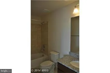 a bathroom with a granite countertop toilet a sink and a mirror