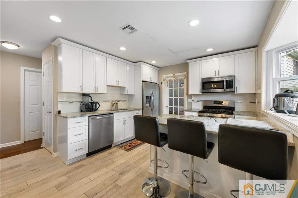 18 Baxter Road Edison, NJ 08817 - Photo 15 of 32 a kitchen with stainless steel appliances kitchen island granite countertop a stove top oven a sink a refrigerator with a dining table and chairs