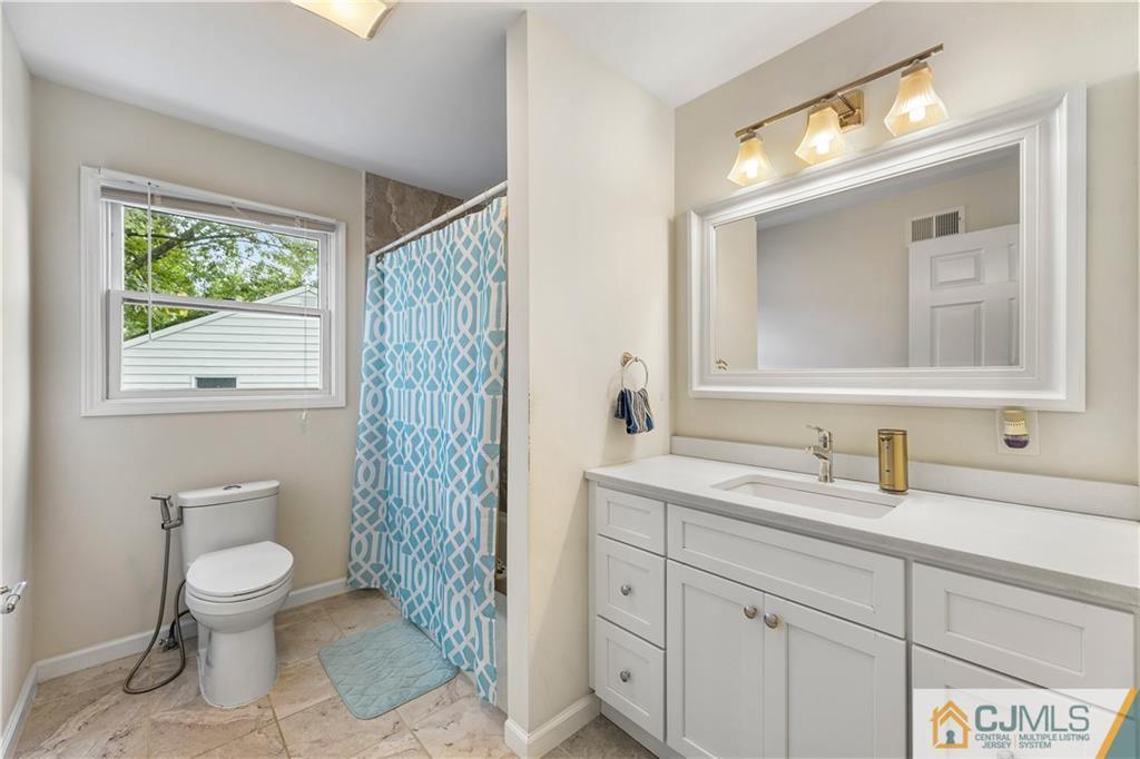 18 Baxter Road Edison, NJ 08817 - Photo 31 of 32 a bathroom with a toilet a sink a mirror a window and vanity